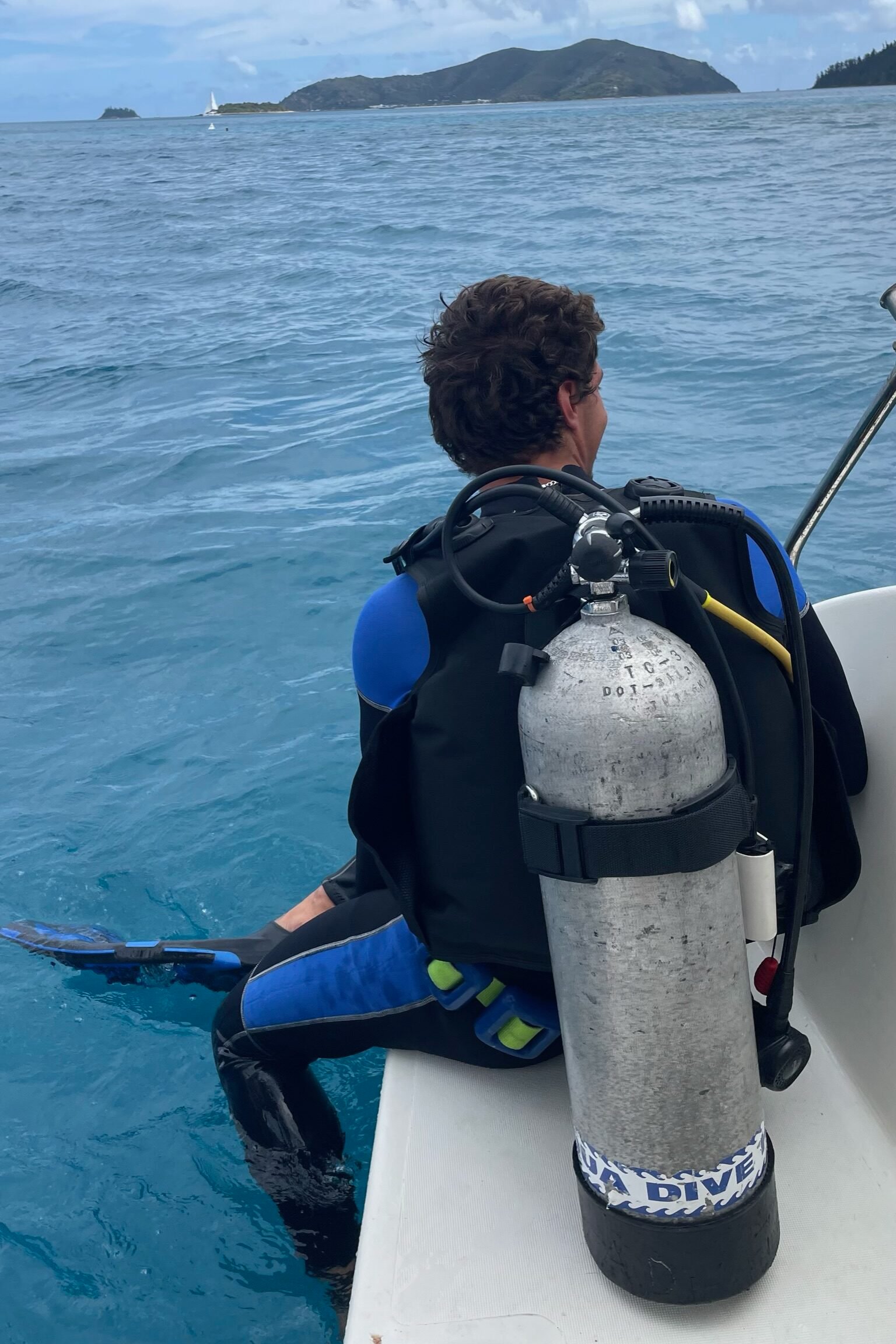 Scuba diver preparing to enter tropical waters from a boat.